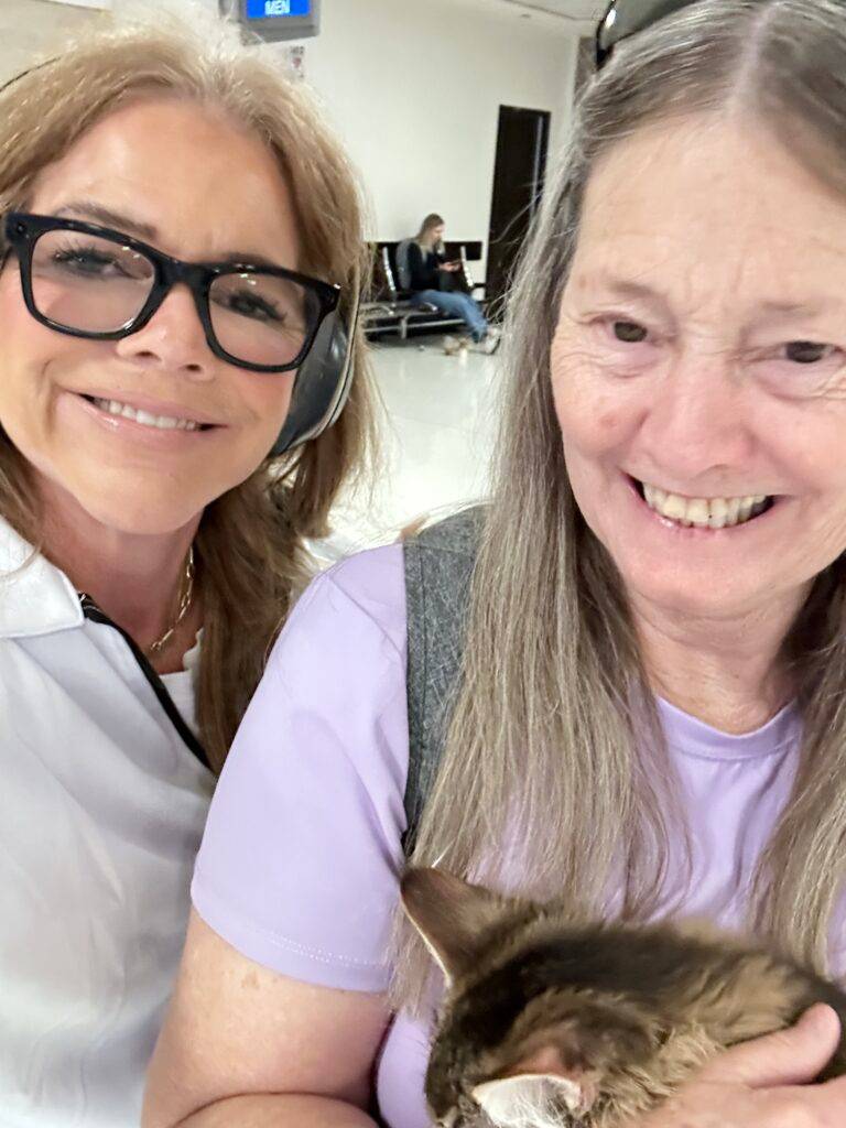 Lucy Appel and a new owner smiling as she holds her brown tabby Maine Coon kitten after an in-cabin delivery to Phoenix Sky Harbor International Airport